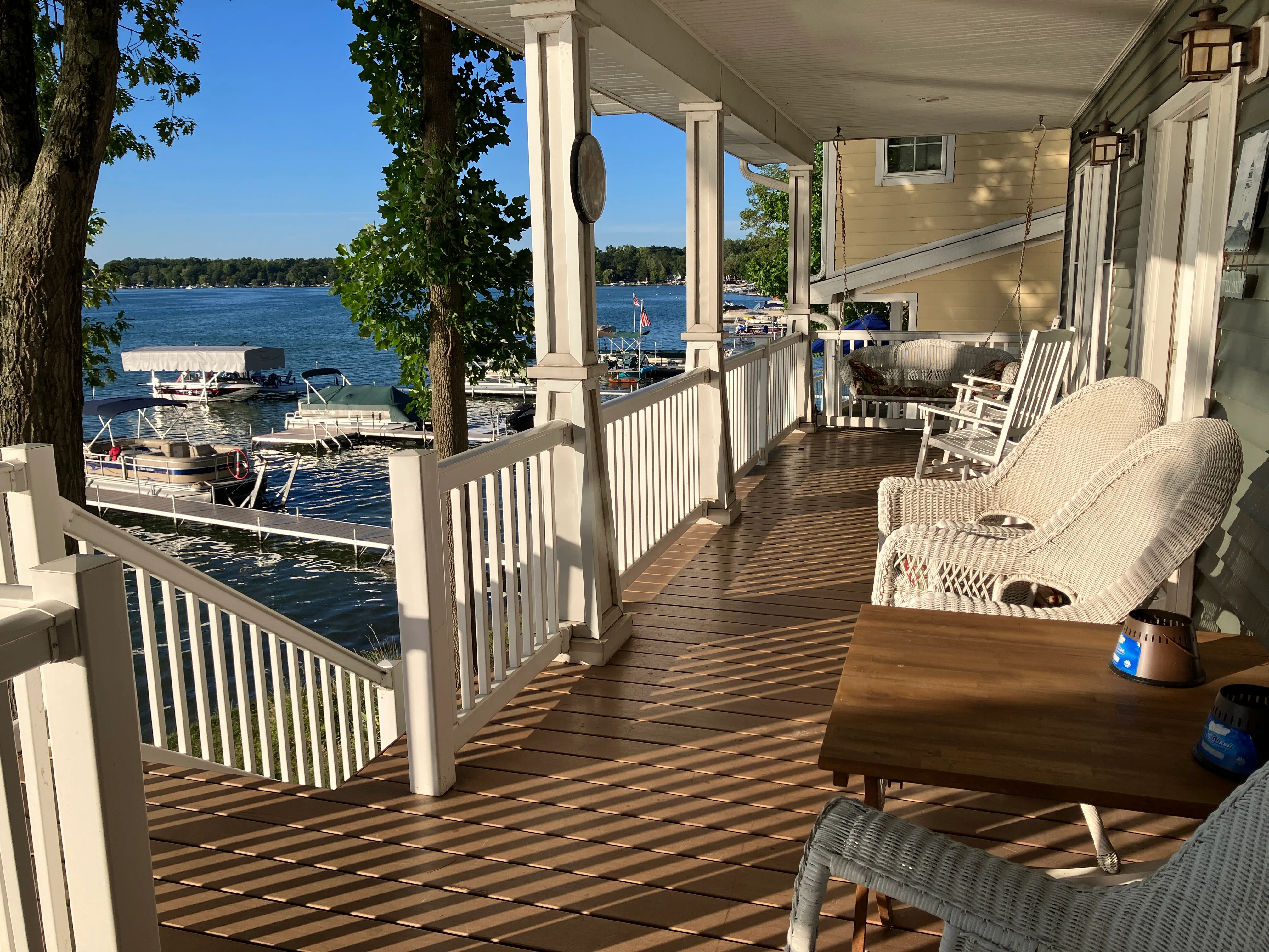 The wraparound lakeside porch with wicker chairs, looking out over the dock.